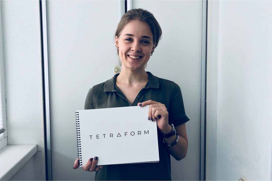 Саша улыбается и держит белый блокнот на спирали с надписью TETRAFORM